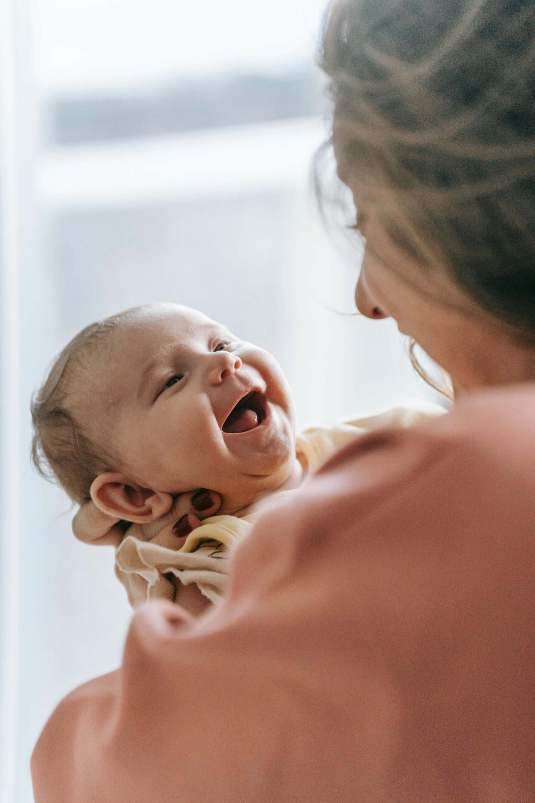A joyful moment of a mother holding a laughing baby in a cozy indoor setting.